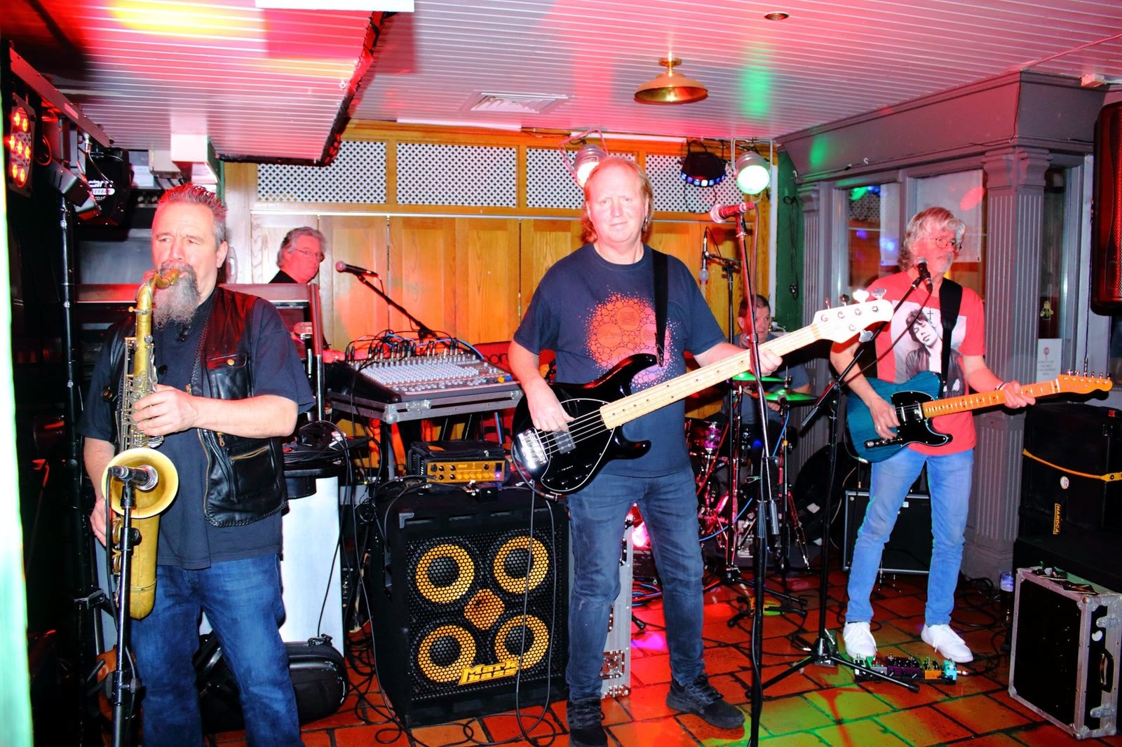 A five-piece band with a saxophone playing in the lounge