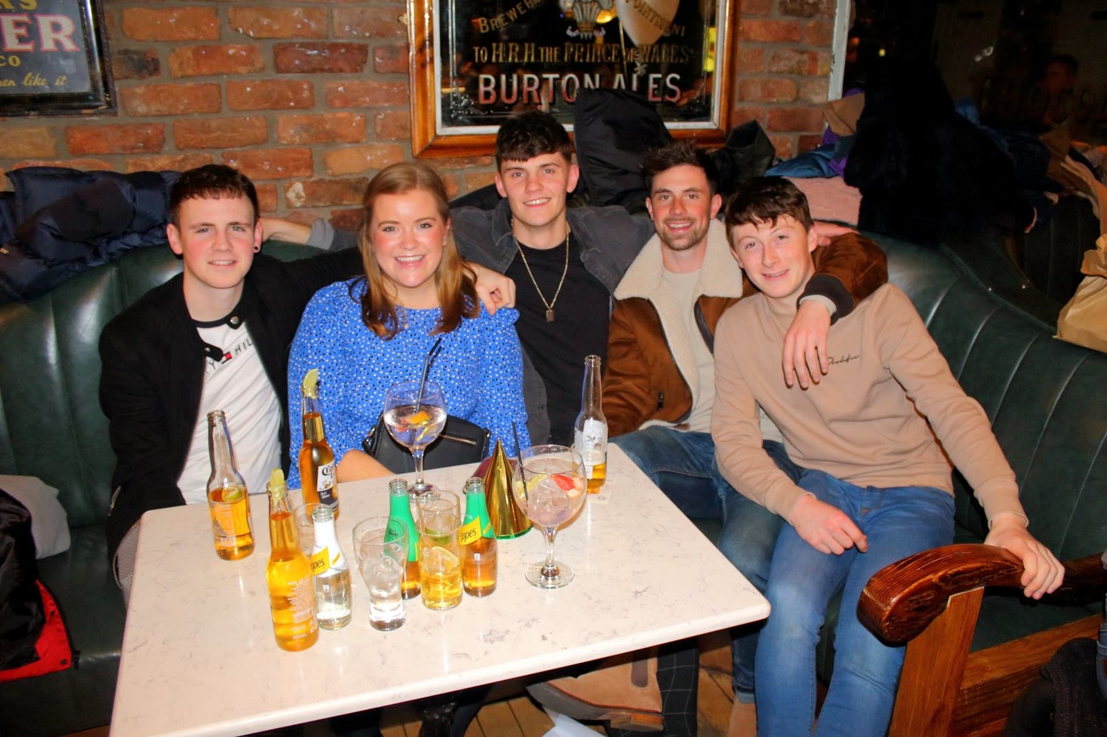 Five friends squeezed into a leather booth under a Burton Ales mirror