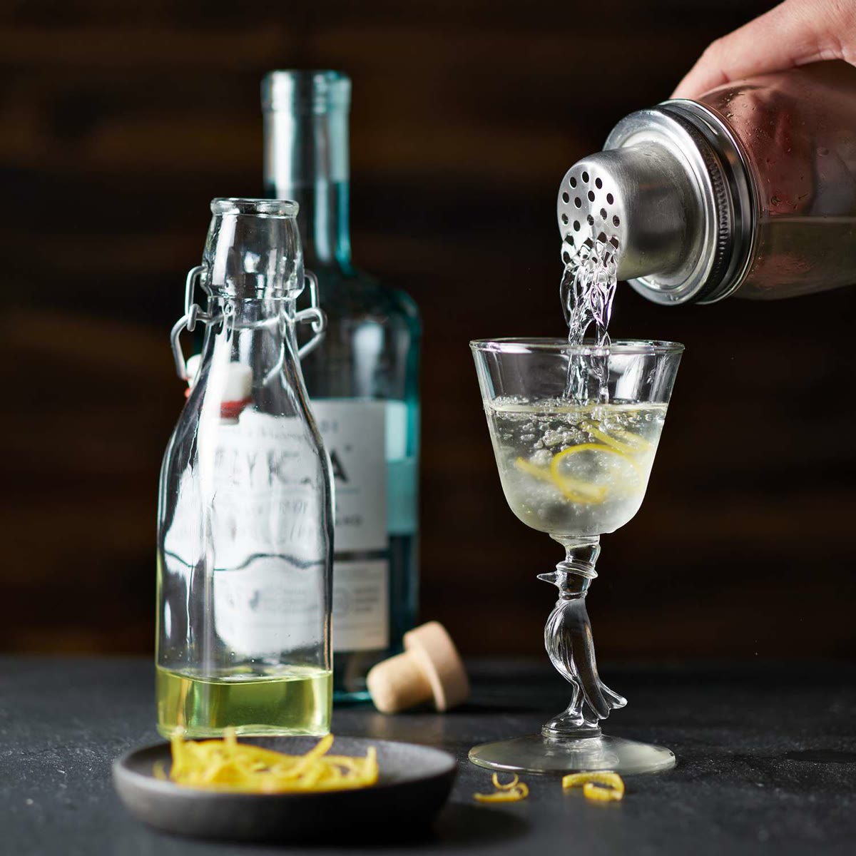A gimlet being poured from a shaker into a coupe glass