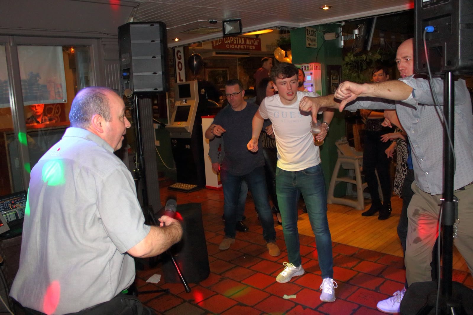 A man dancing with his arms out on a packed lounge floor