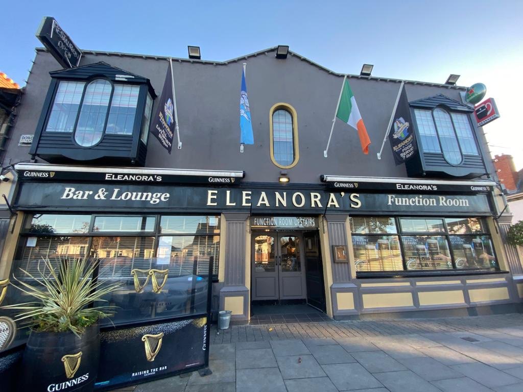 The front of Eleanora's by day, with its bar and lounge signs, an Irish flag and a Guinness awning