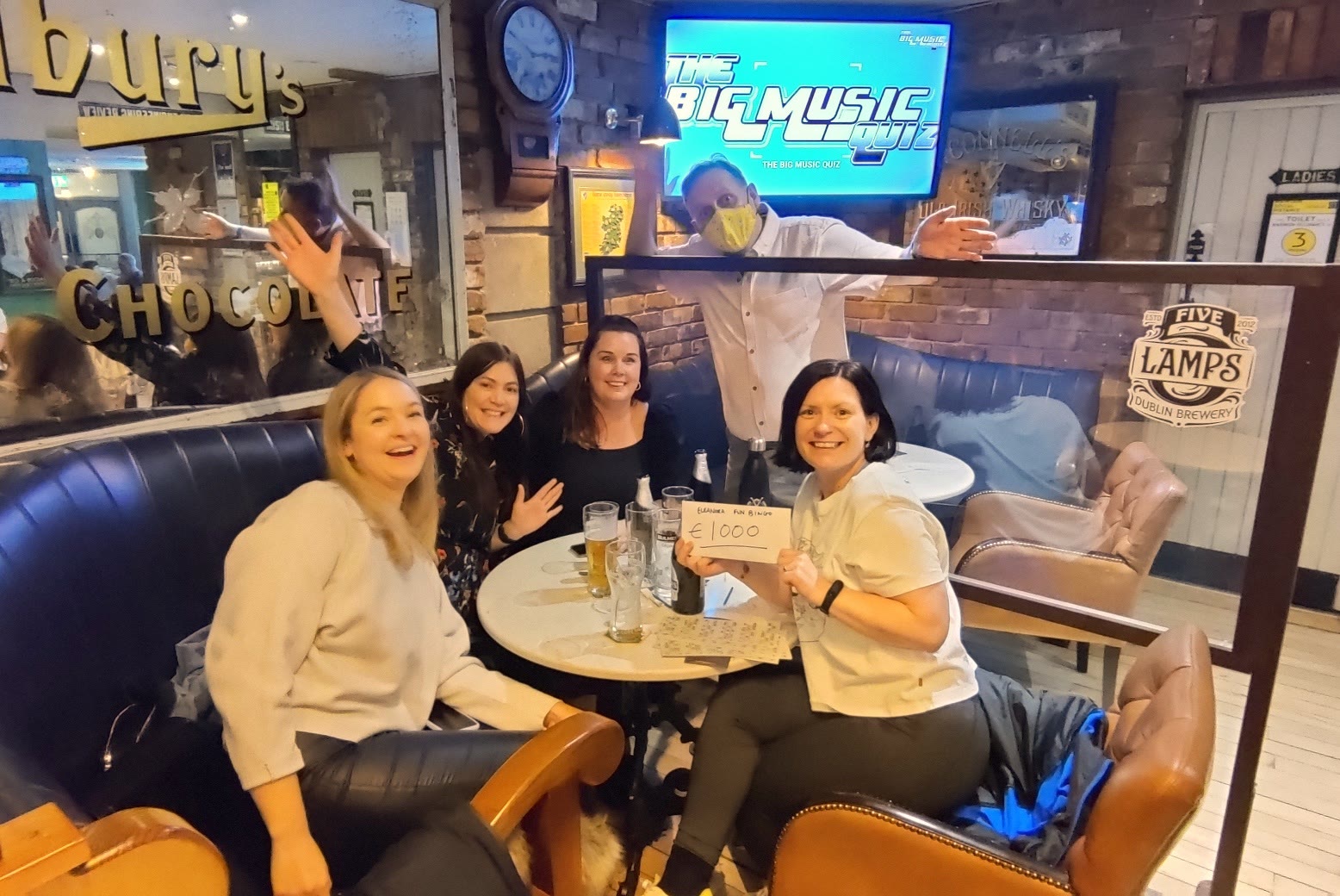 Four friends in a booth raising their glasses