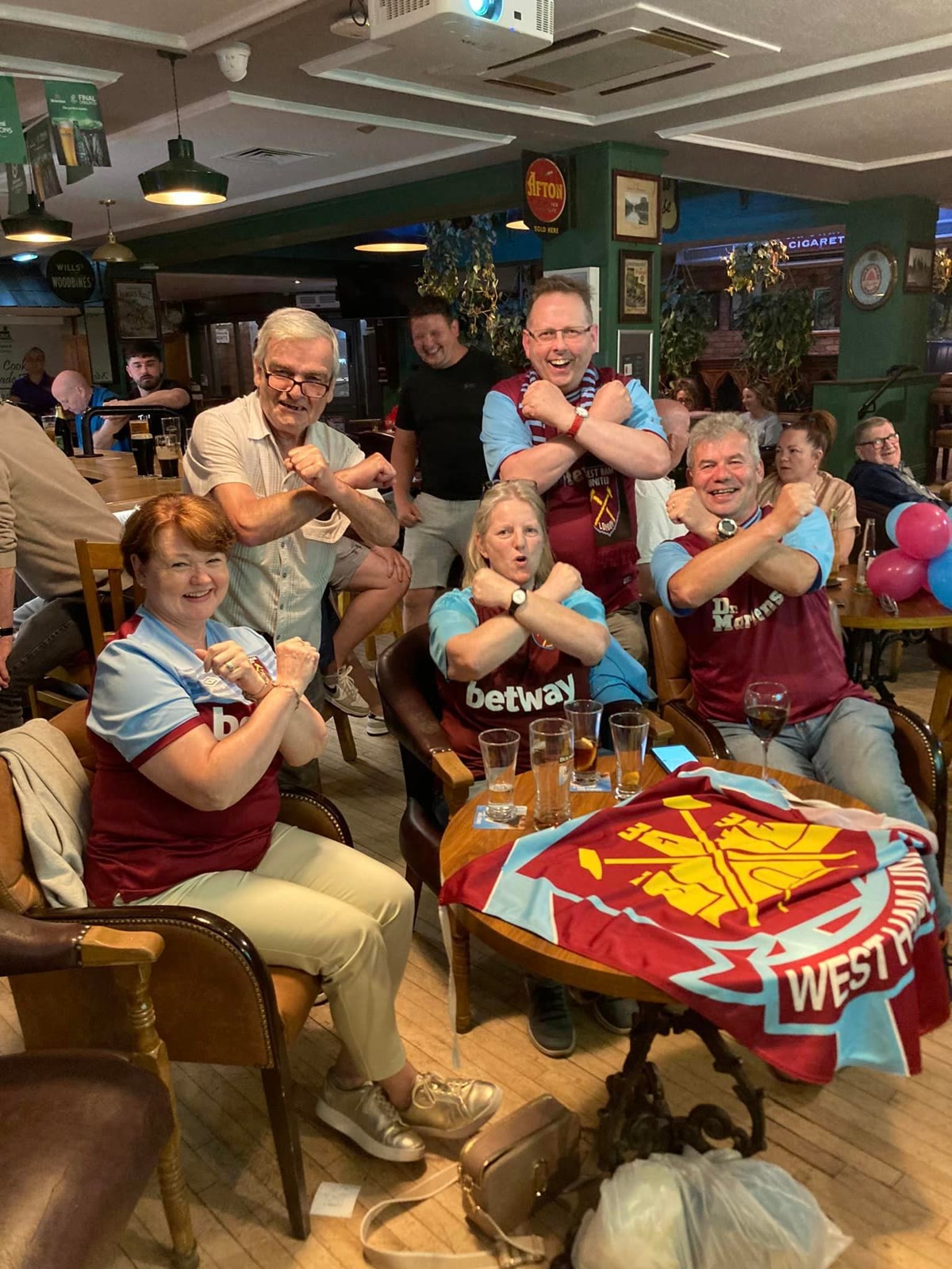 Football fans in team scarves cheering round a table