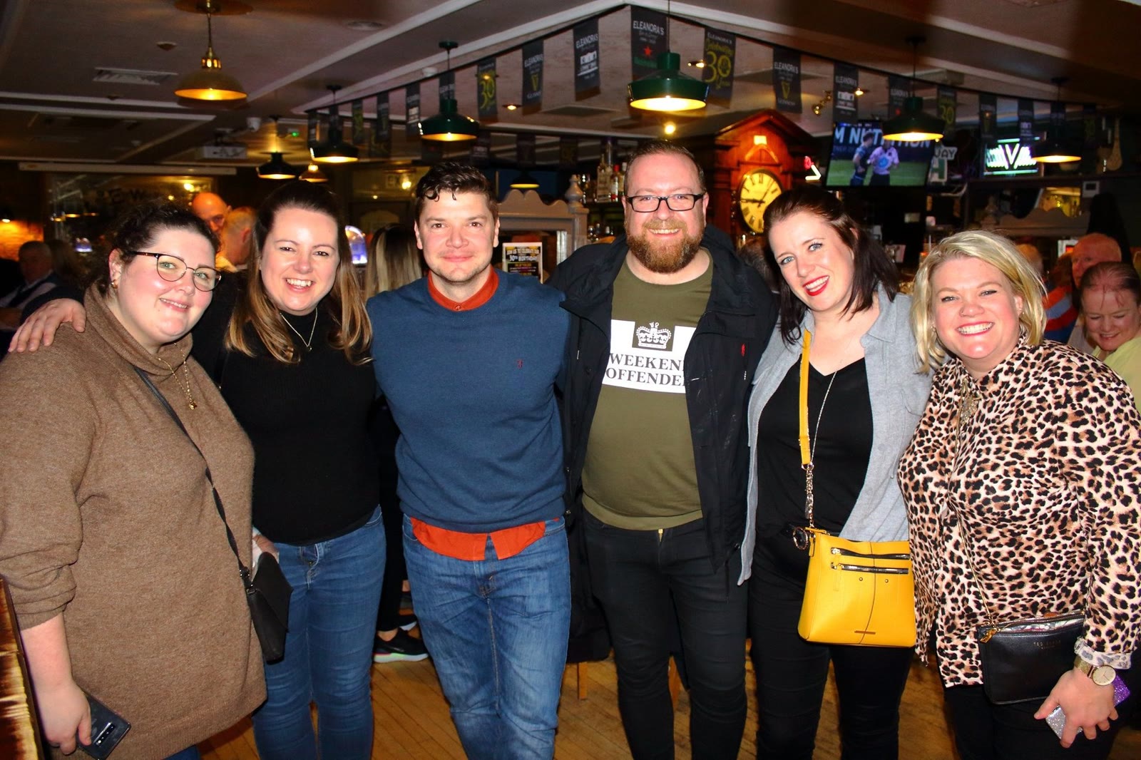 A group of friends standing arm in arm in the bar