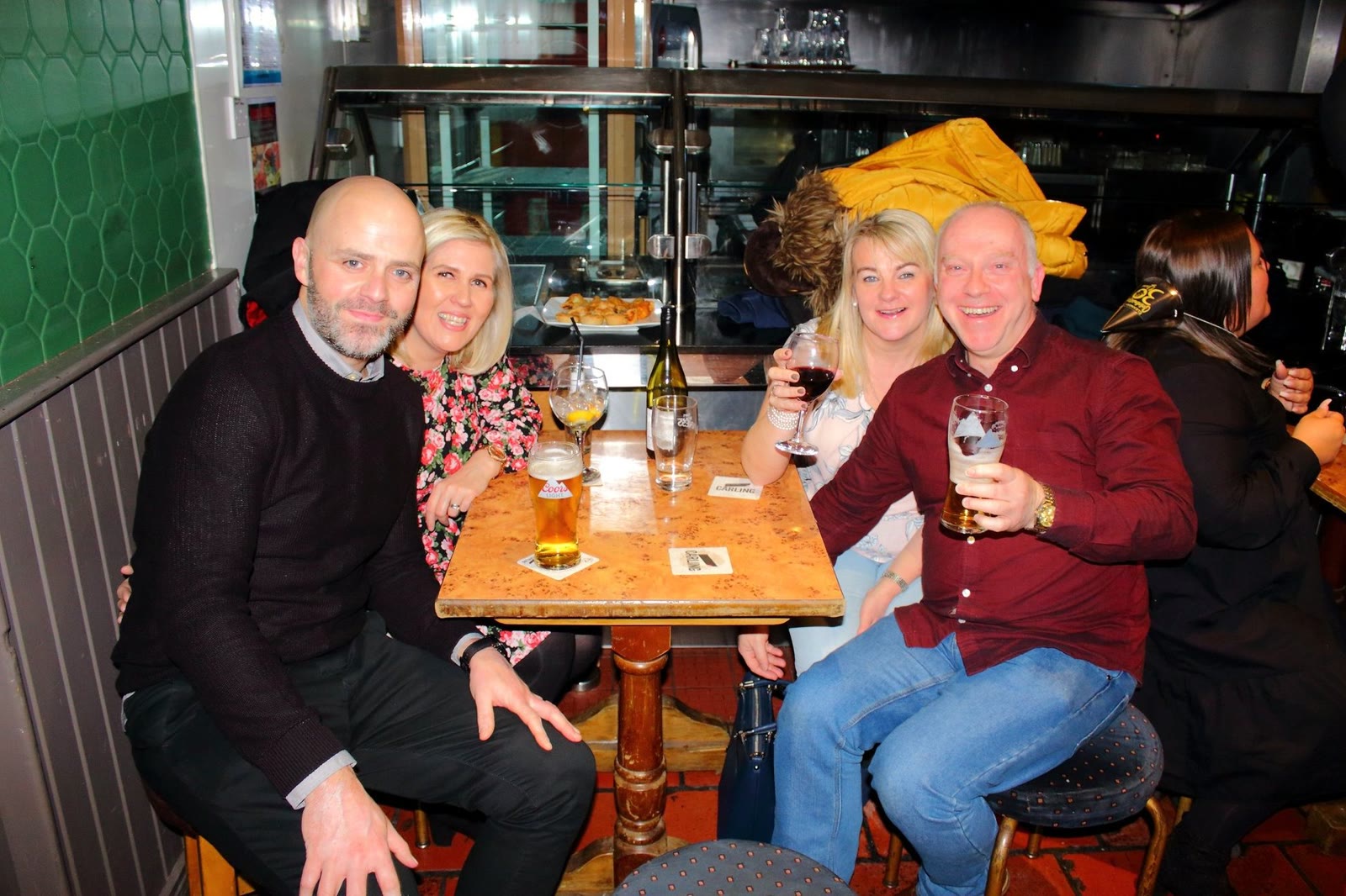 Friends with pints of stout and glasses of wine round a table in the bar
