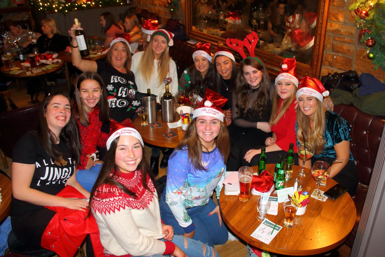 A big group in Christmas hats celebrating round a table